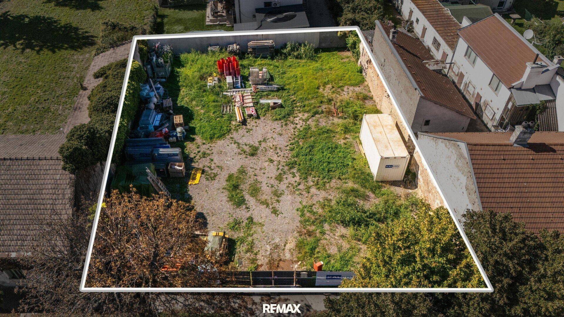 Vogelperspektive eines eingegrenzten Grundstücks mit unregelmäßigem Bewuchs und Bauutensilien.
