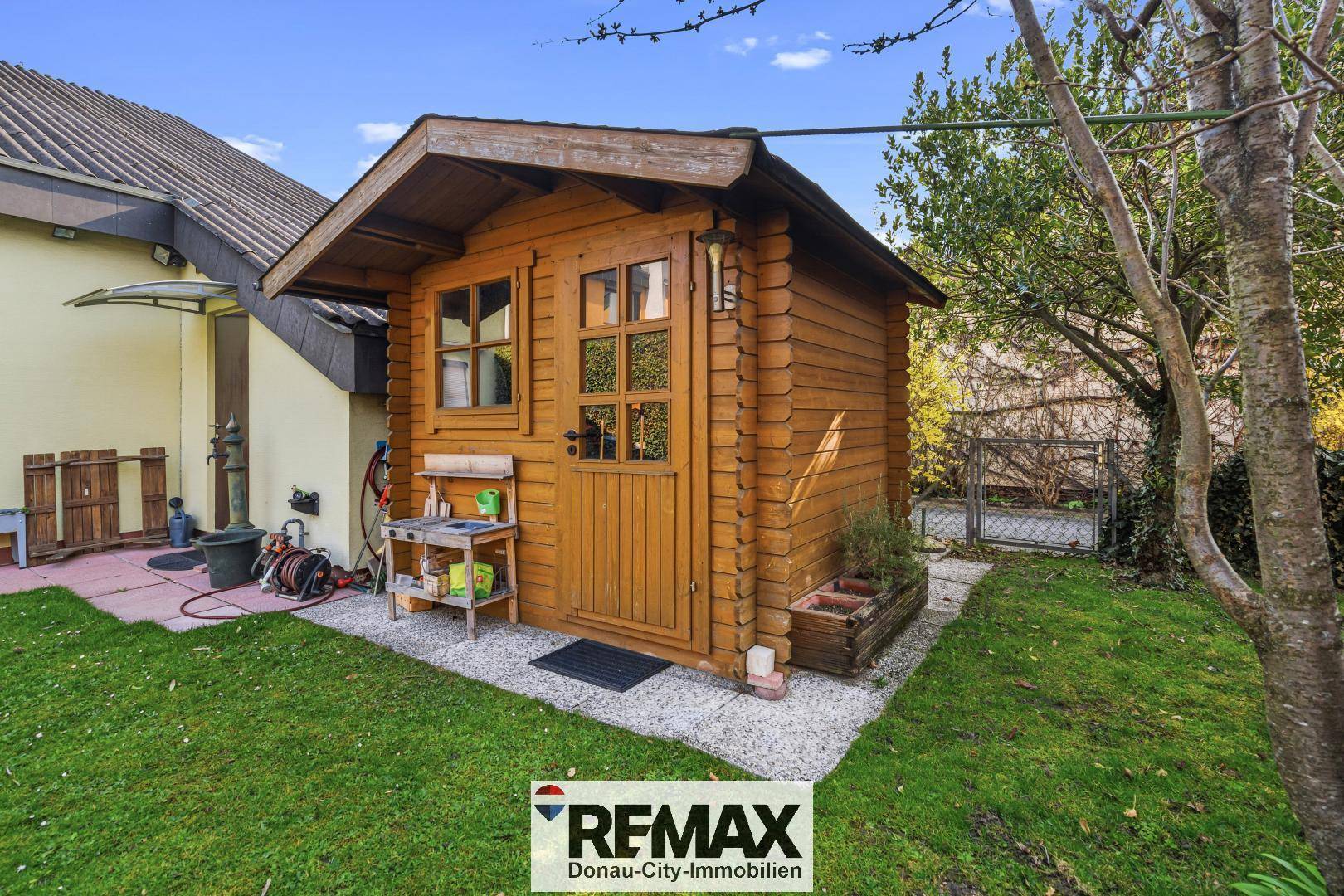 Charmantes Gartenhaus aus Holz mit Fenstern und kleiner Veranda im Grünen.