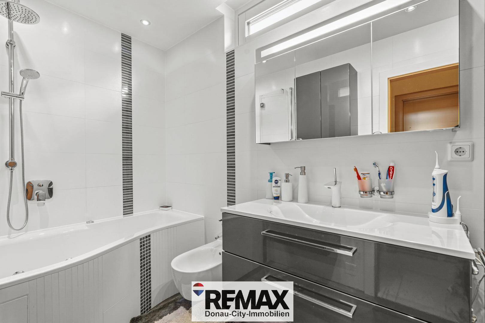 Modernes Badezimmer mit Badewanne, Bidet, Doppelwaschbecken und großformatigen Fliesen.