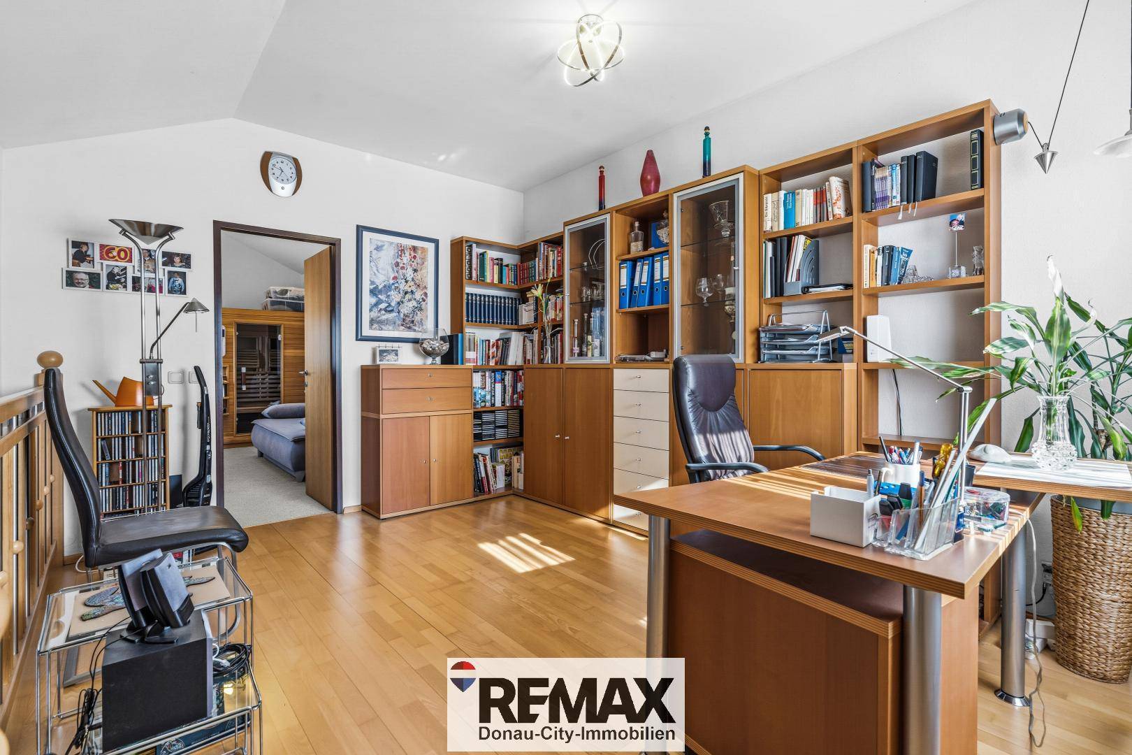 Helles Büro auf der Galerie mit Holzregalen, Schreibtisch und Blick in den Wohnbereich.
