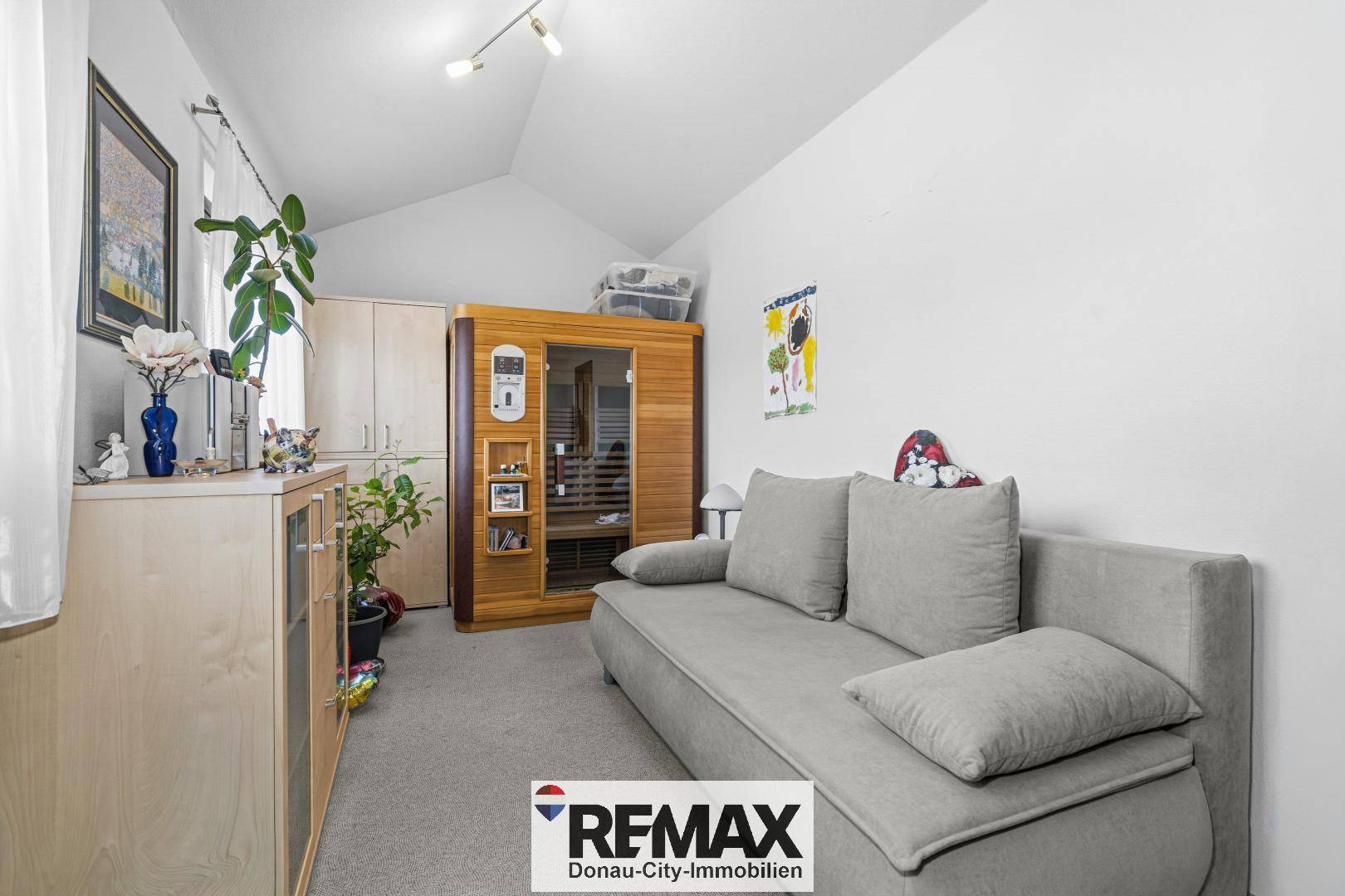Zimmer mit Sofa, Teppichboden und einer Infrarot-Saunakabine für Wellness zu Hause.