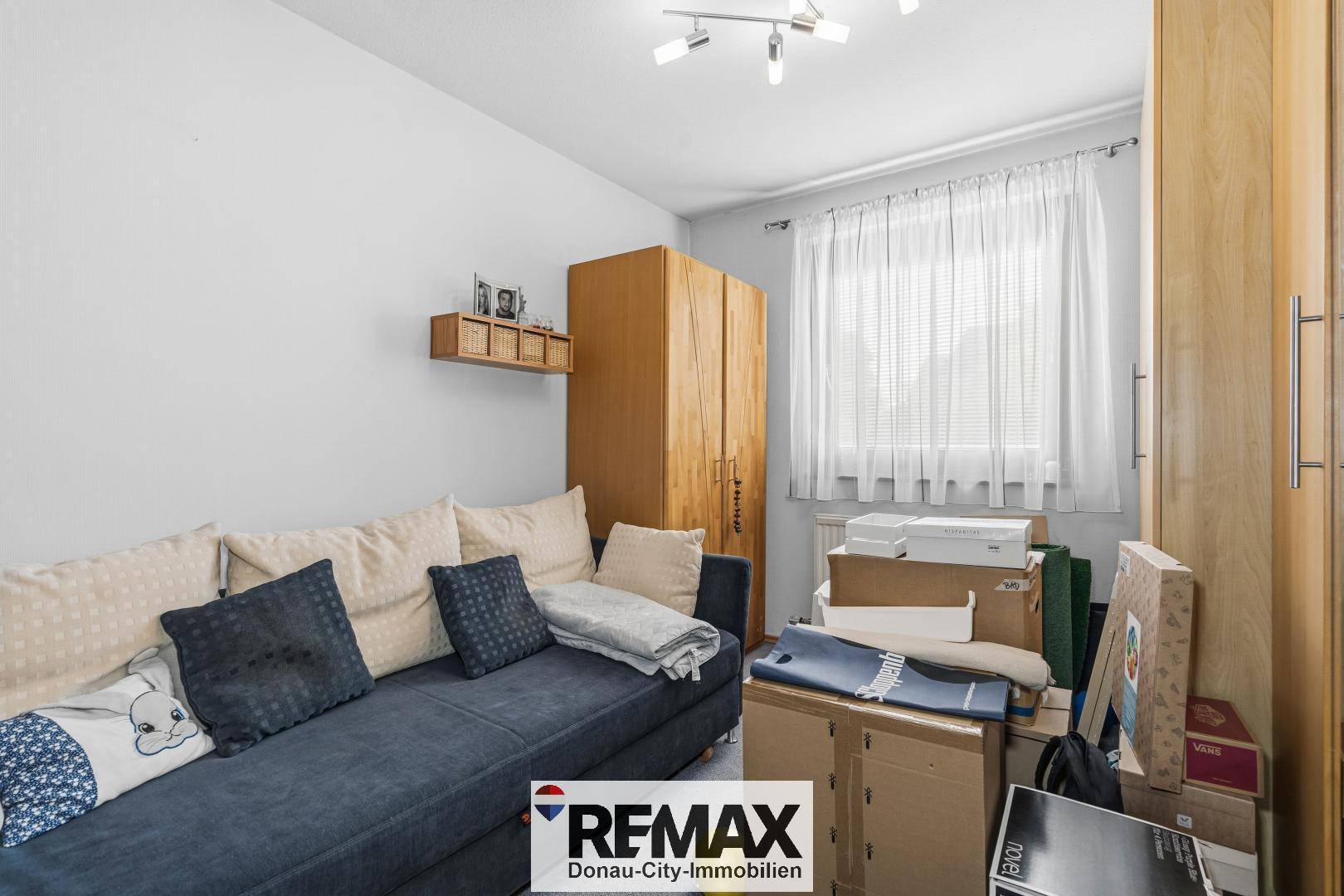 Schlafzimmer mit Sofa, Fenster und Stauraum, das als Gäste- oder Kinderzimmer genutzt werden kann.