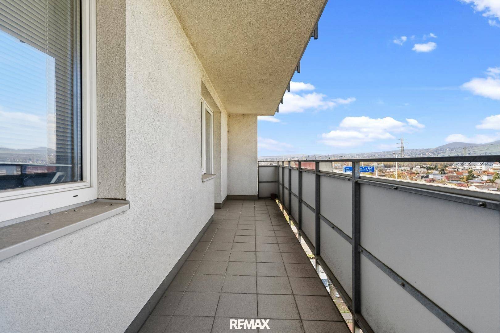 Langer, schmaler Balkon mit Fliesenboden und weitem Blick über die Umgebung.