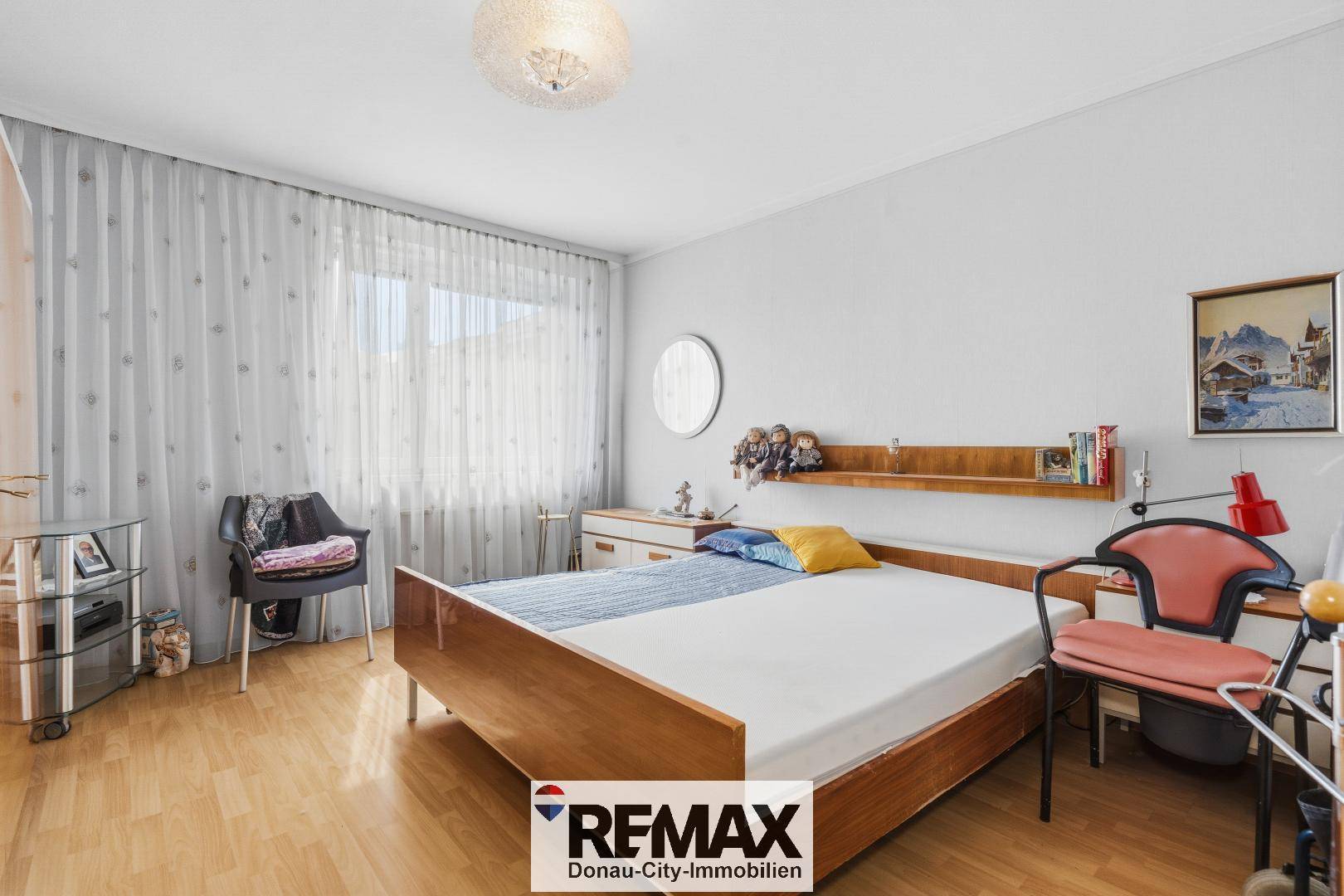 Schlafzimmer mit Holzfußboden, einem Doppelbett und einem Fenster mit Vorhängen.