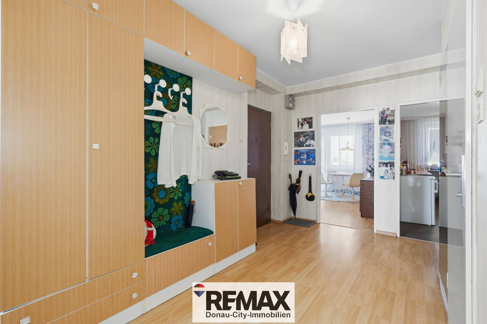 Eingangsbereich mit Holzfußboden, integrierter Garderobe und farbenfroher Tapete.