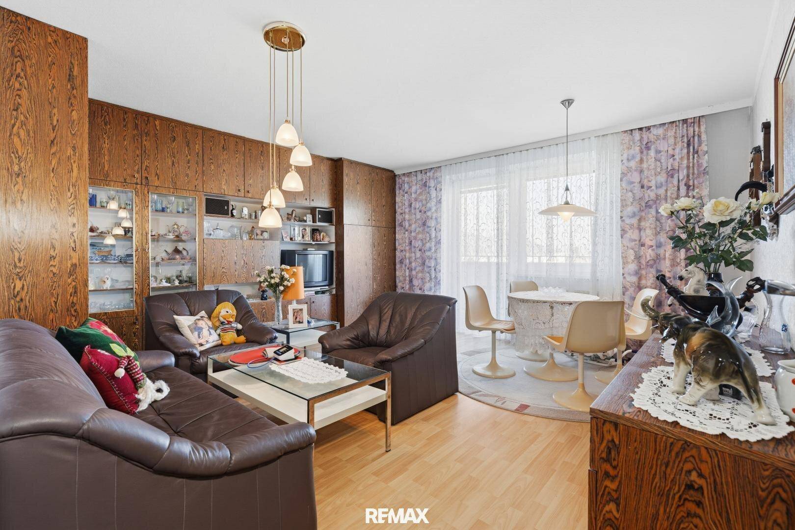 Gemütlicher Wohn-Essbereich mit Holzvertäfelung, Ledersofas und einem Esstisch am Fenster.