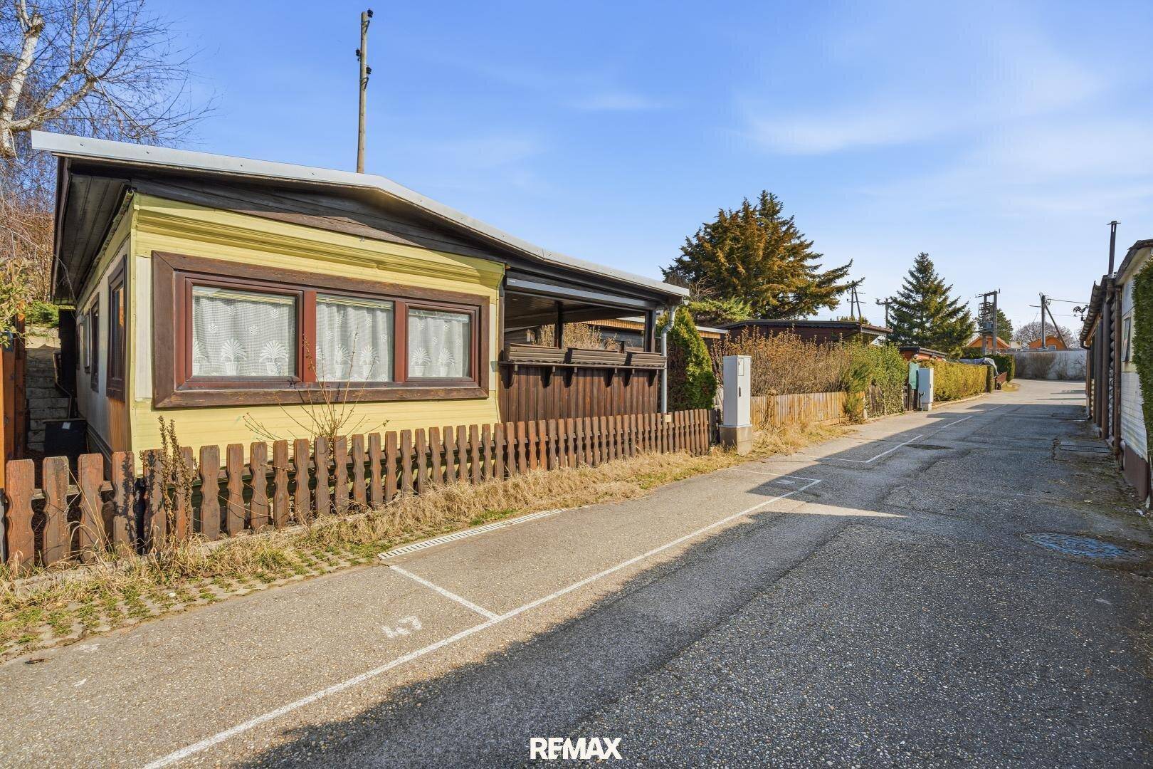 Seitenansicht des Ferienhauses mit Zufahrtsstraße und umgebender ländlicher Landschaft.