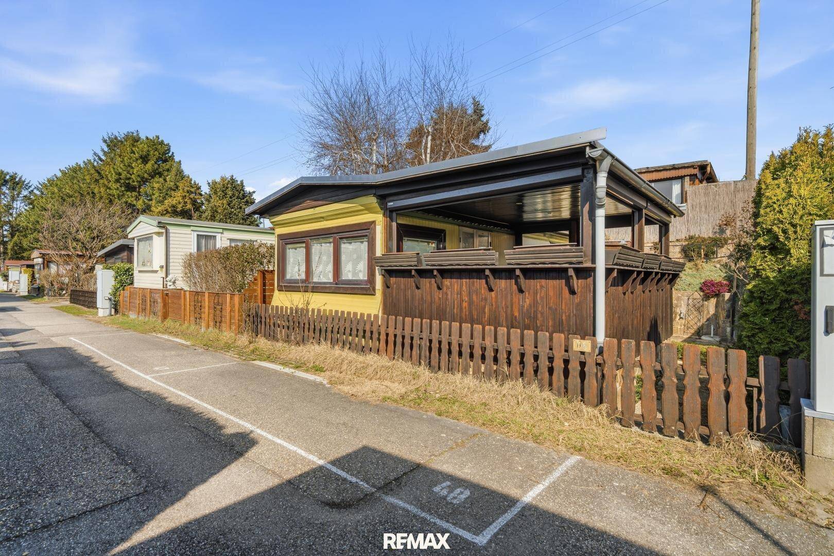 Ansicht des Ferienhauses von der Straße mit überdachtem Außenbereich und Holzzaun.