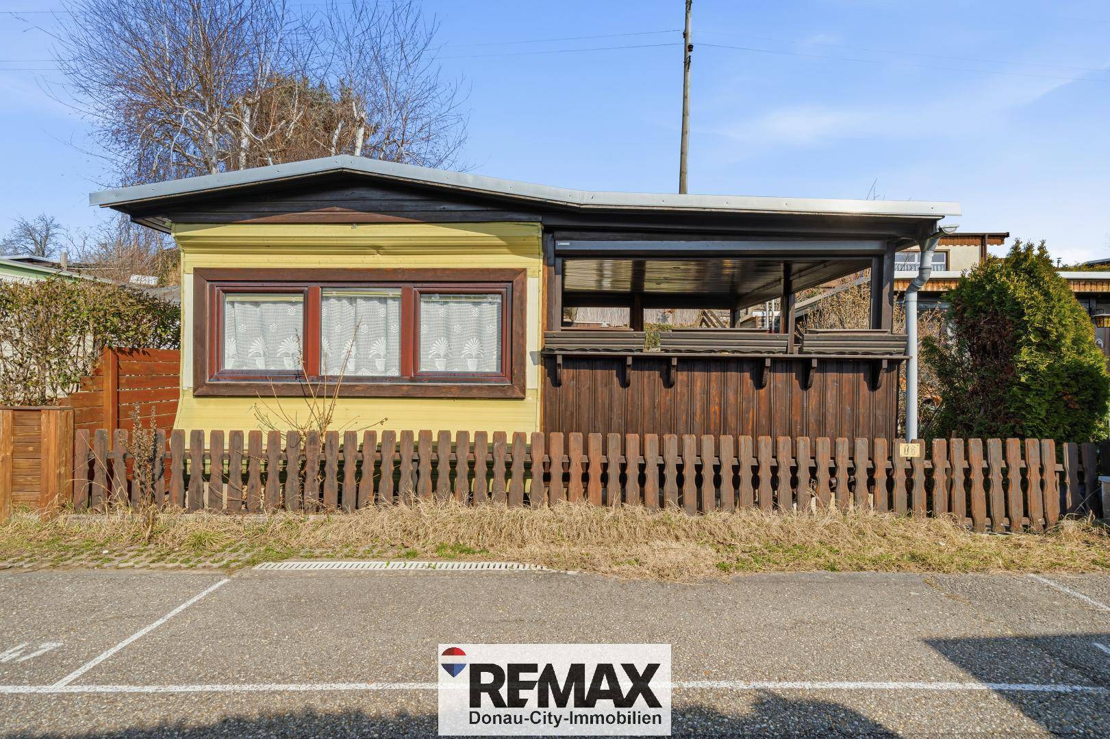Vorderansicht des Chalets mit gelber Fassade, Fenstern und einem traditionellen Holzzaun.