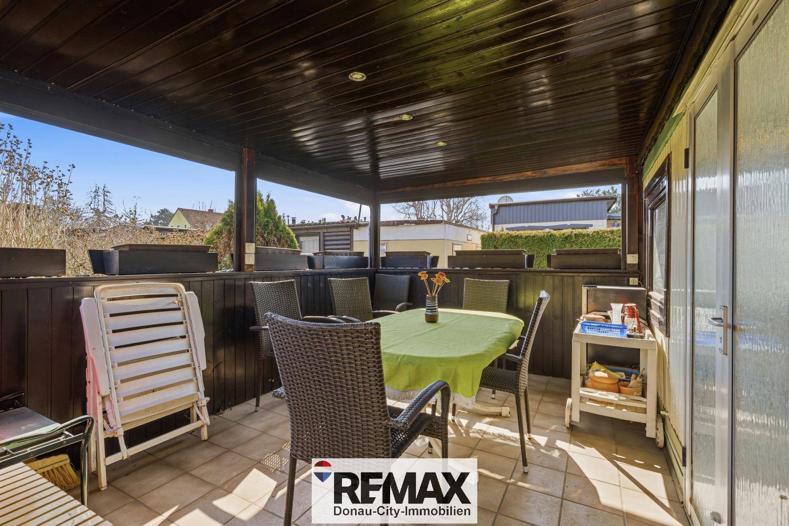 Überdachte Terrasse mit Esstisch und Stühlen, ideal für Mahlzeiten im Freien.