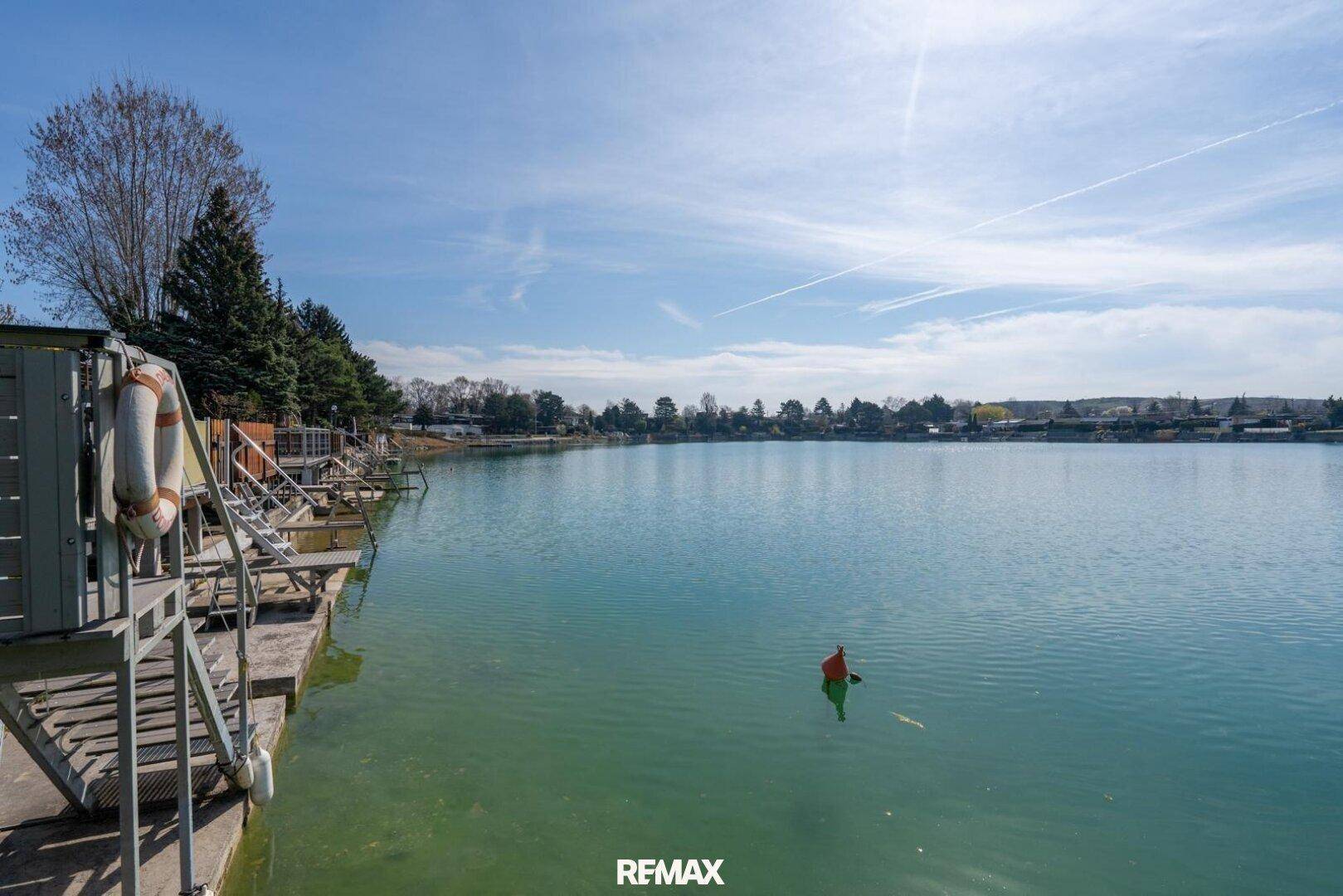 Weitläufiger Blick über den See mit Uferbebauung und klarem, blauem Wasser.