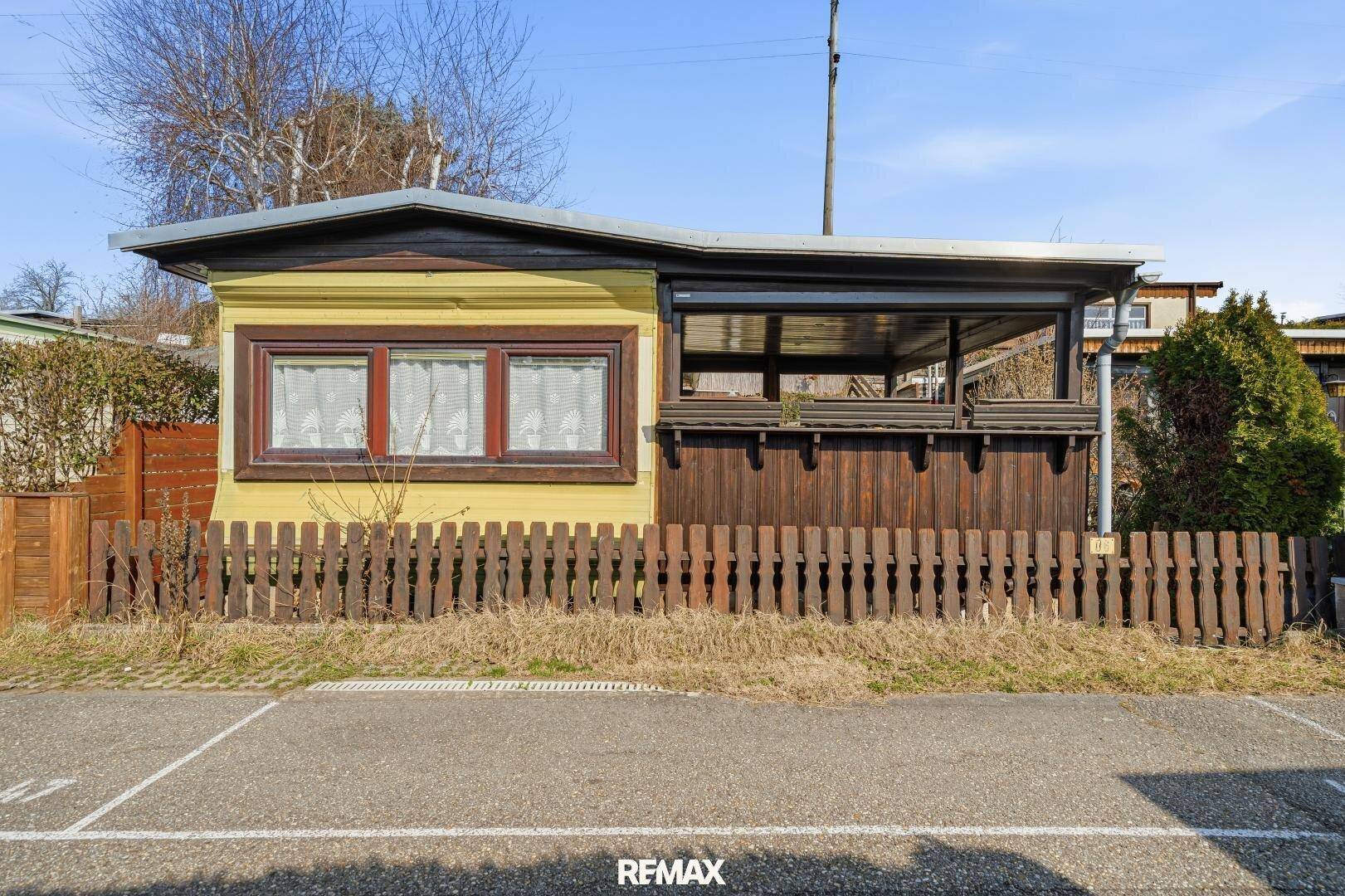 Vorderansicht des kleinen Ferienhauses mit gelber Fassade und überdachter Veranda.