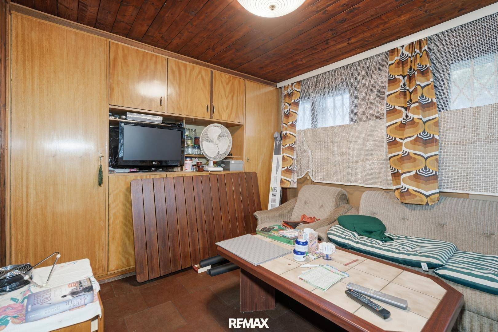 Rustikales Wohnzimmer mit Holzdecke, Einbauschränken und gemütlicher Sitzecke im Vintage-Stil.