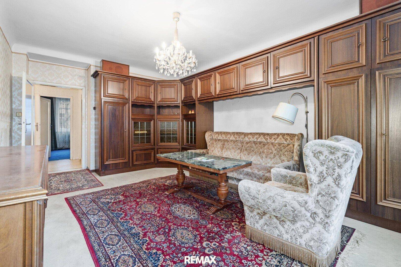 Traditionelles Wohnzimmer mit dunklen Holzmöbeln, Teppich und Kronleuchter, im klassischen Stil.