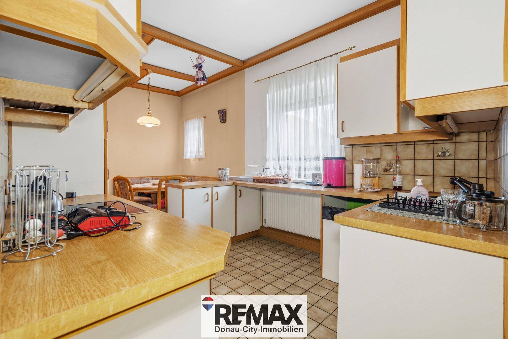 Geräumige Küche mit Essbereich, weißen Schränken und Holzdetails an der Decke.