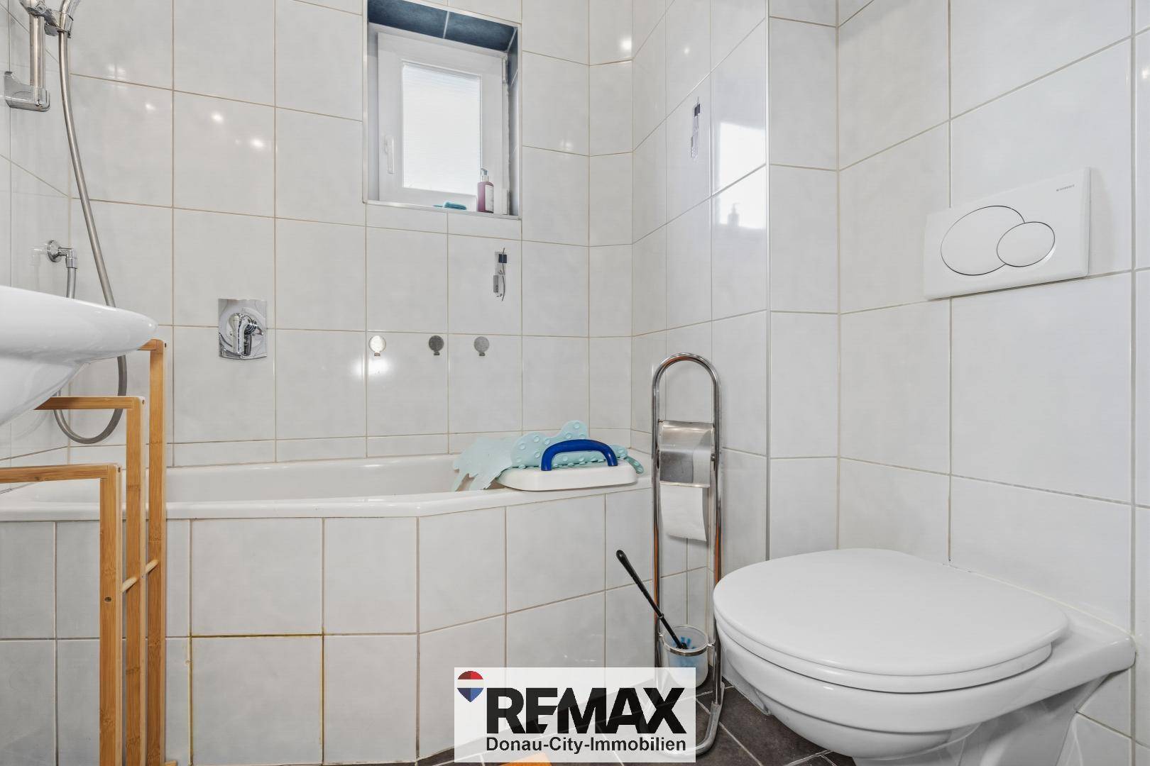 Helles Badezimmer mit Badewanne, Toilette und weißen Fliesen.