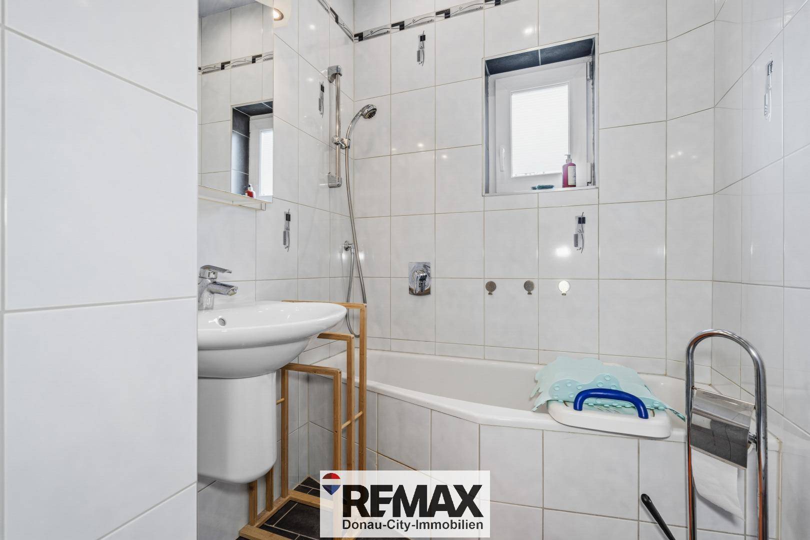 Gefliestes Badezimmer mit Badewanne, Dusche und Waschbecken.