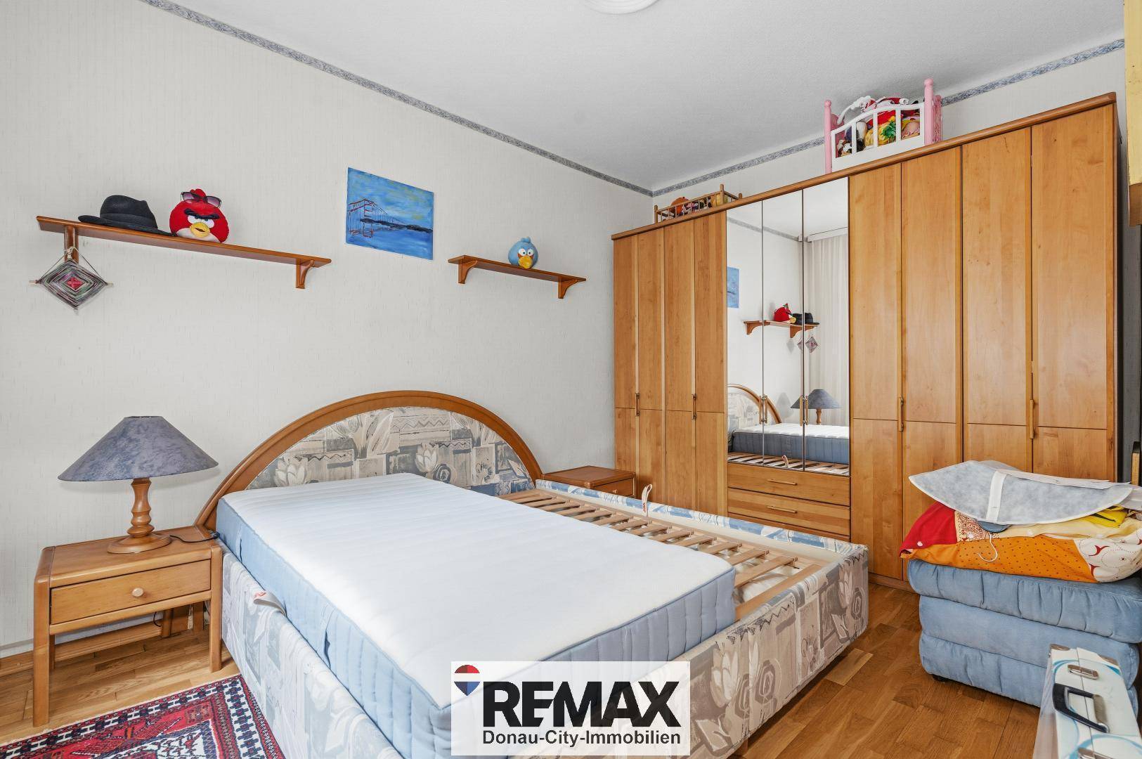 Schlafzimmer mit Holzbett, großem Kleiderschrank und Parkettboden.