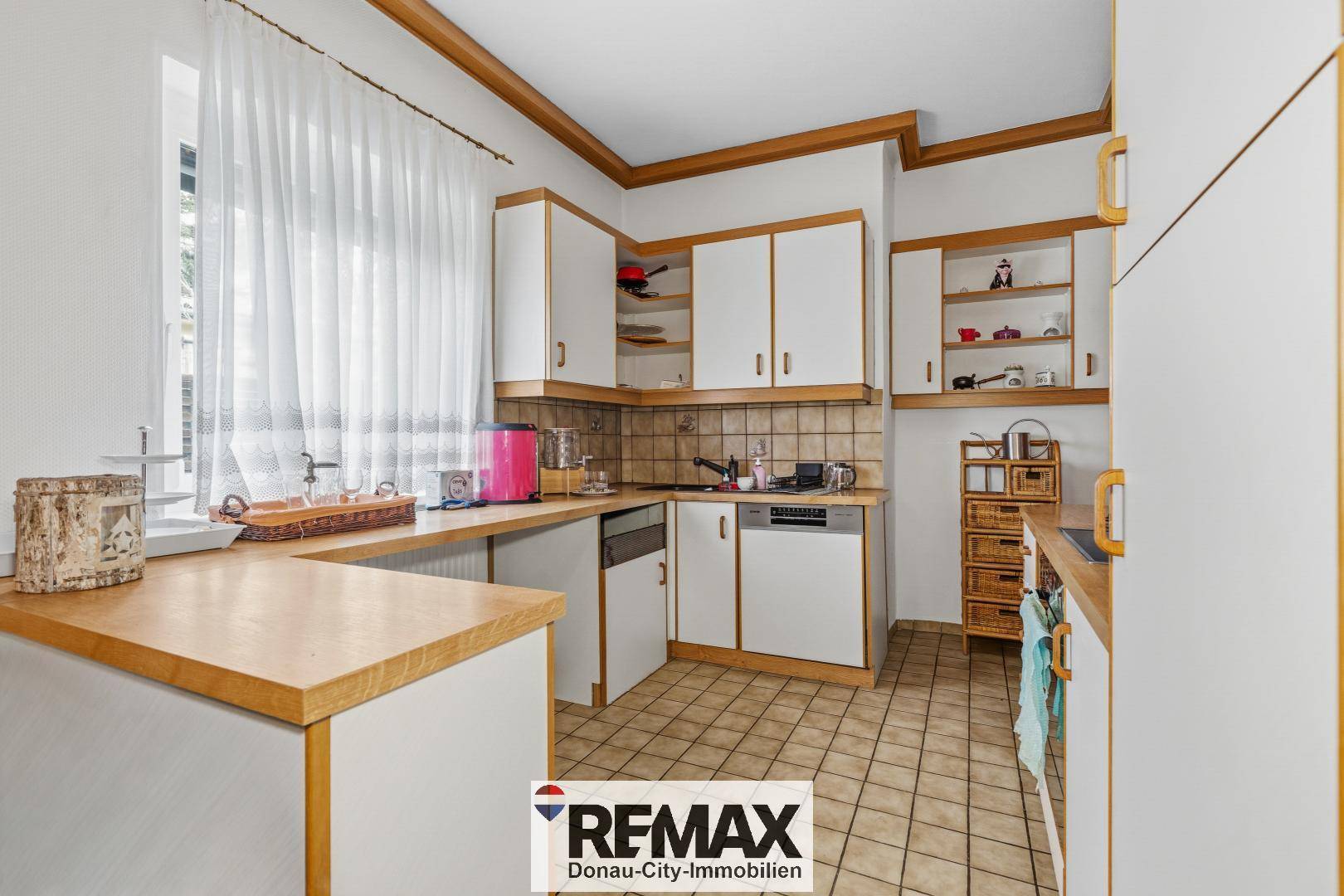 Funktionale Küche mit weißen Schränken, Holz-Arbeitsplatten und Fliesenboden.