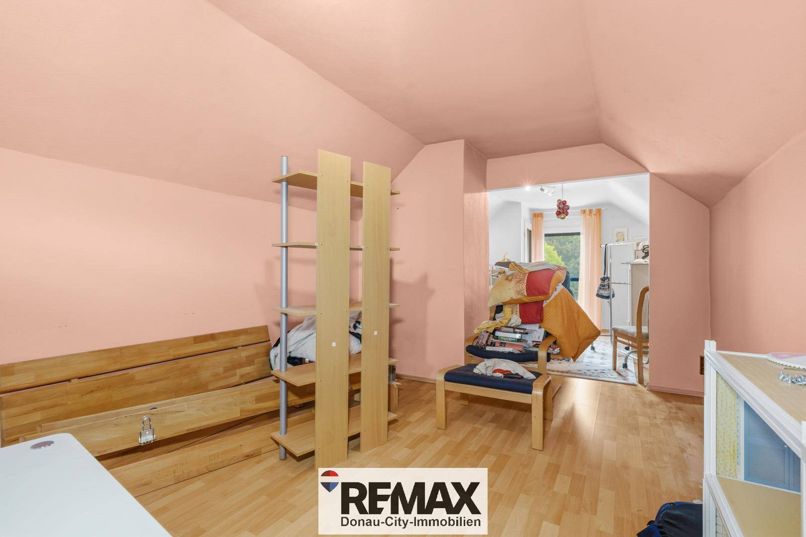 Geräumiges Dachgeschosszimmer mit Parkettboden und Zugang zu einem weiteren Raum.