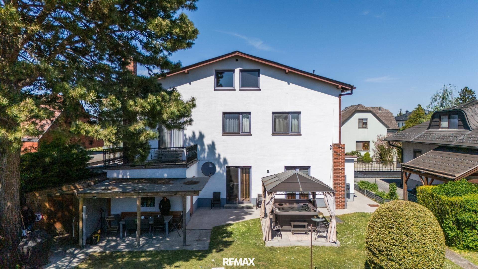 Rückseite des Hauses mit großer Terrasse, Balkon und einem gemütlichen Pavillon im Garten.