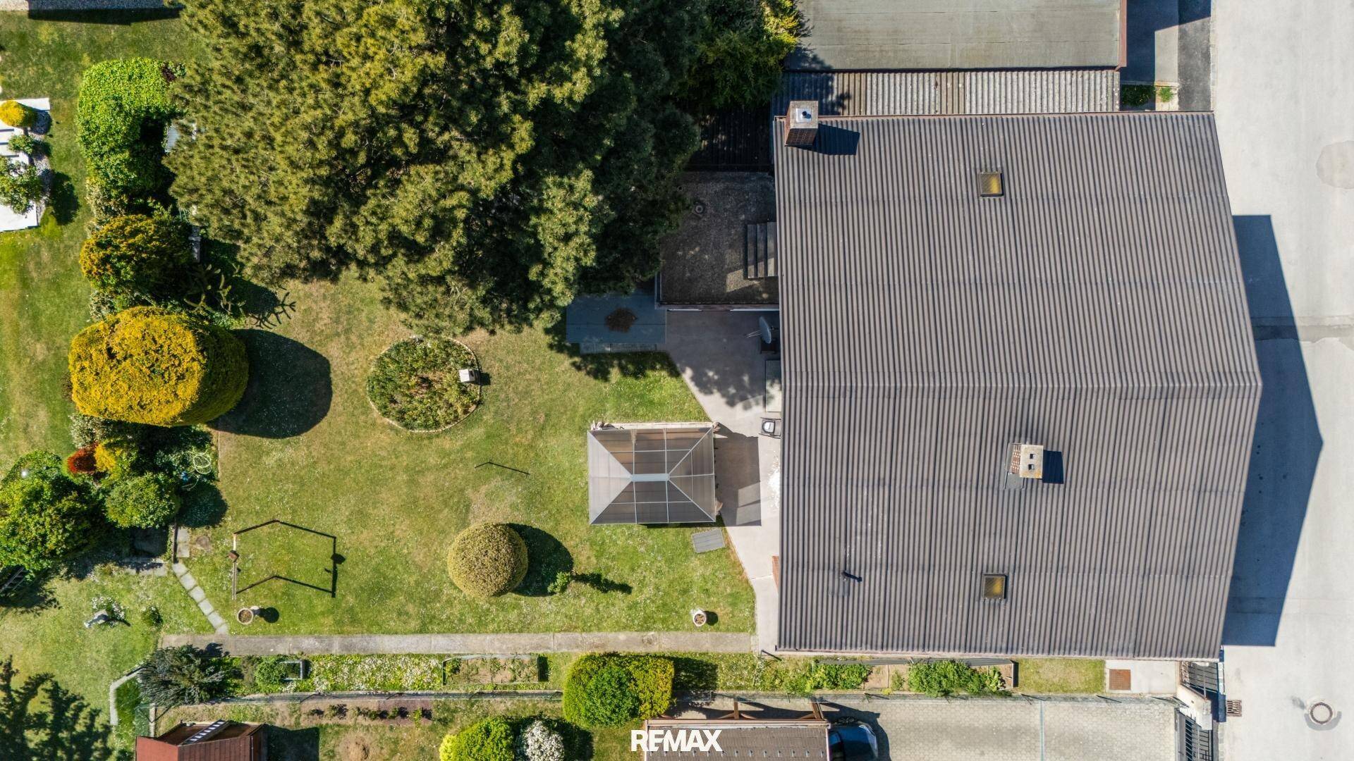 Draufsicht auf das Haus und den weitläufigen Garten mit Baumbestand und gepflegten Grünflächen.