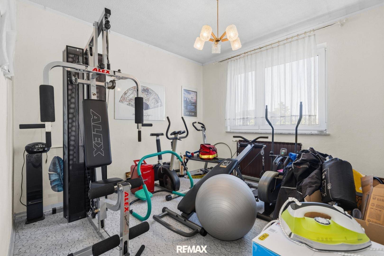 Hobbyraum mit verschiedenen Fitnessgeräten und einem Fenster, das für Belüftung sorgt.