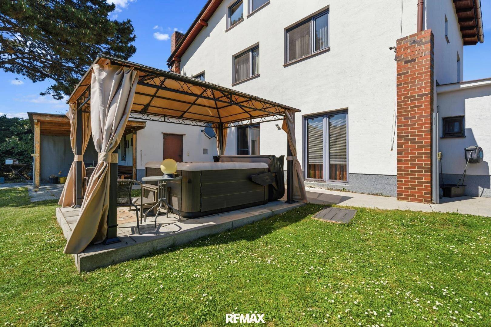 Gartenbereich mit einem überdachten Whirlpool und einer gemütlichen Sitzecke im Freien.