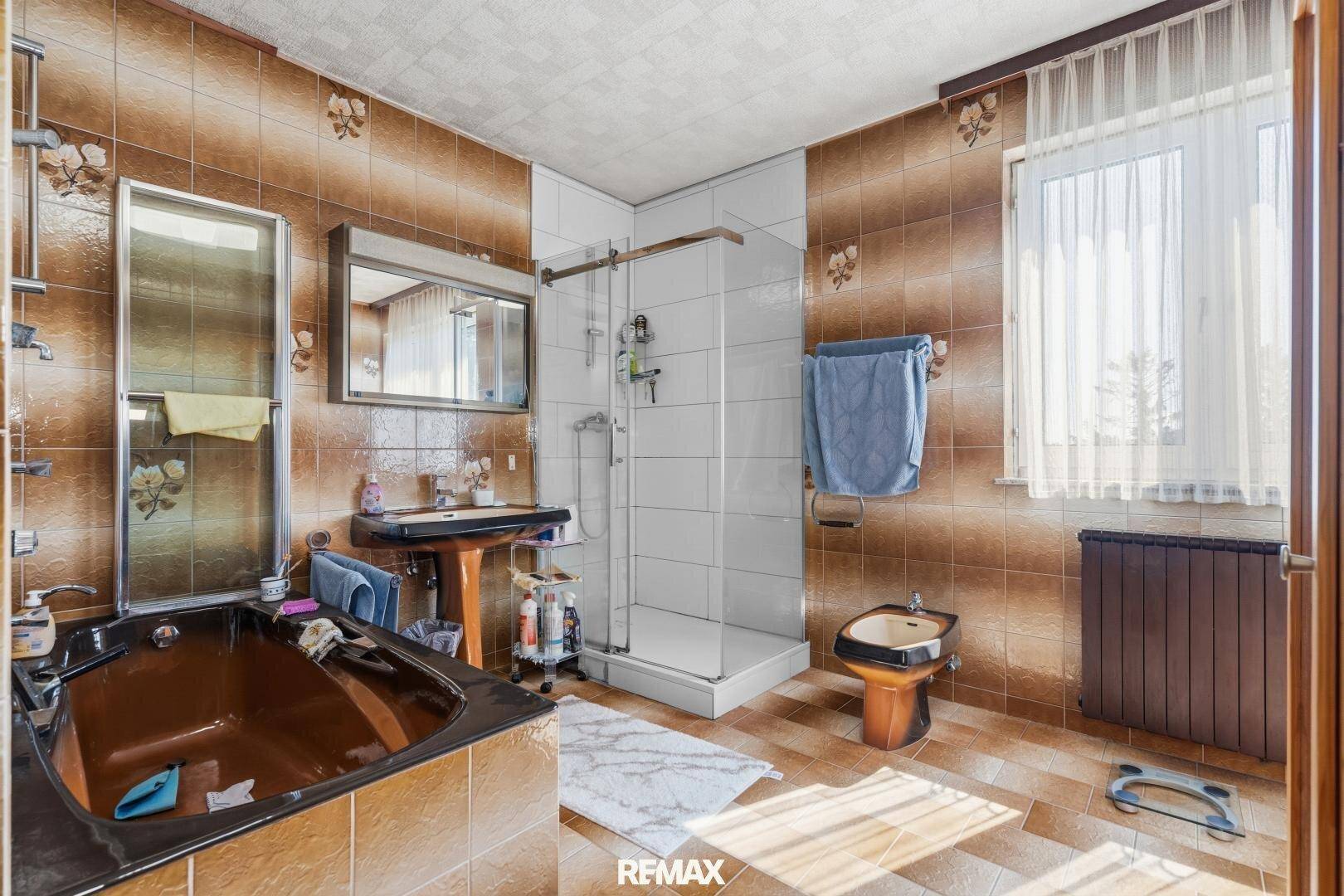Badezimmer im 80er-Jahre-Stil mit braunen Fliesen, Badewanne, Dusche und Bidet.