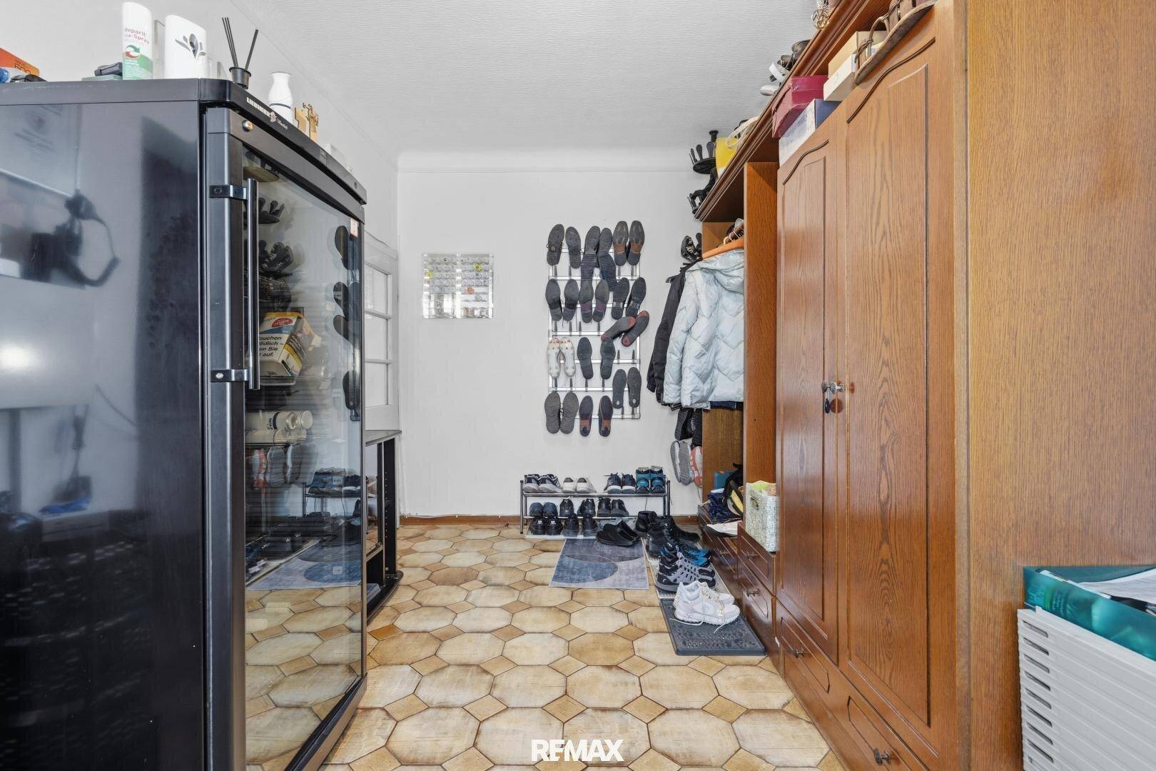Praktischer Abstellraum mit vielen Schuhregalen und einem großen Holzschrank für zusätzlichen Stauraum.