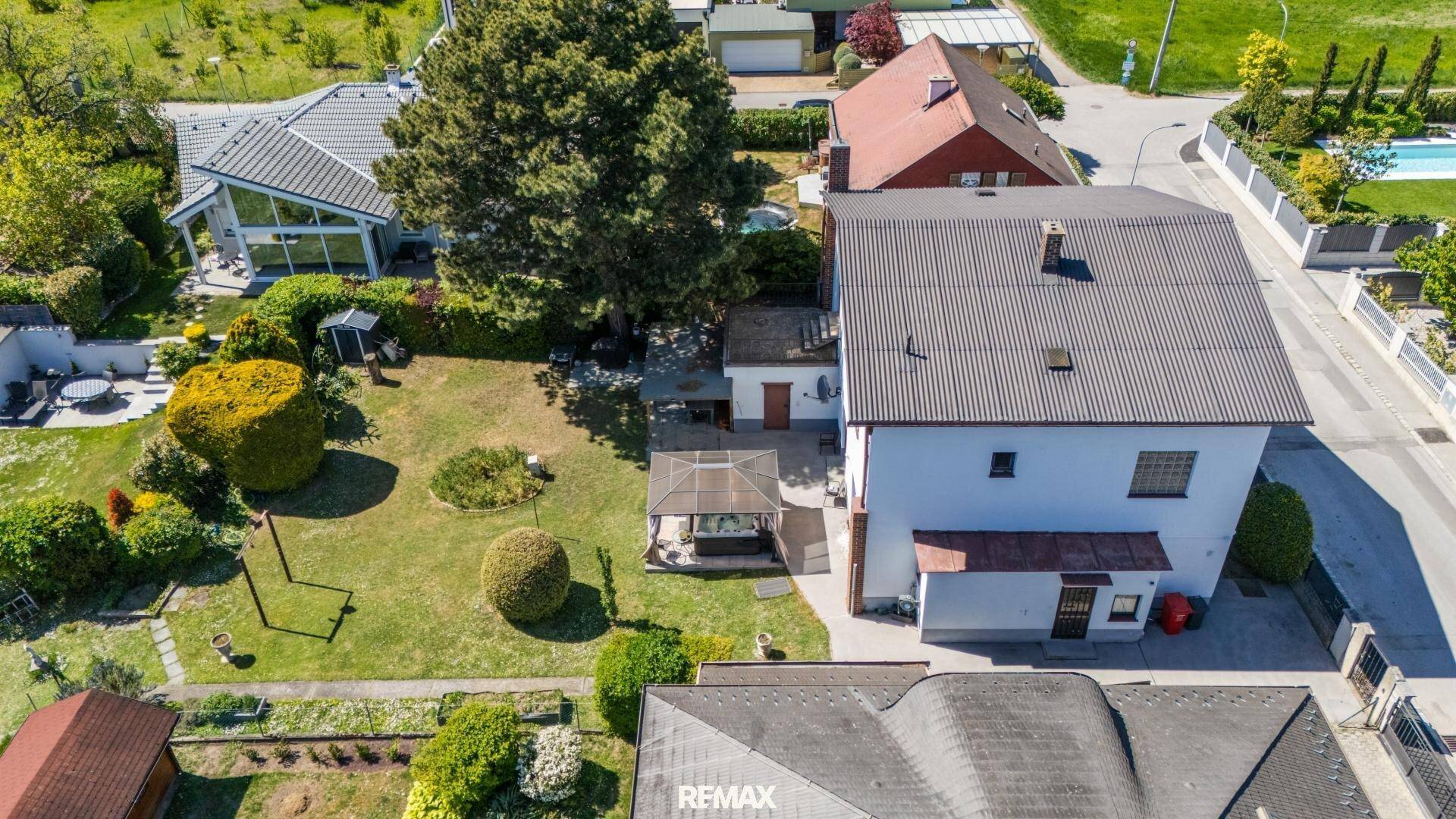 Luftaufnahme eines Einfamilienhauses mit großem, gepflegten Garten und umliegender Wohnbebauung.