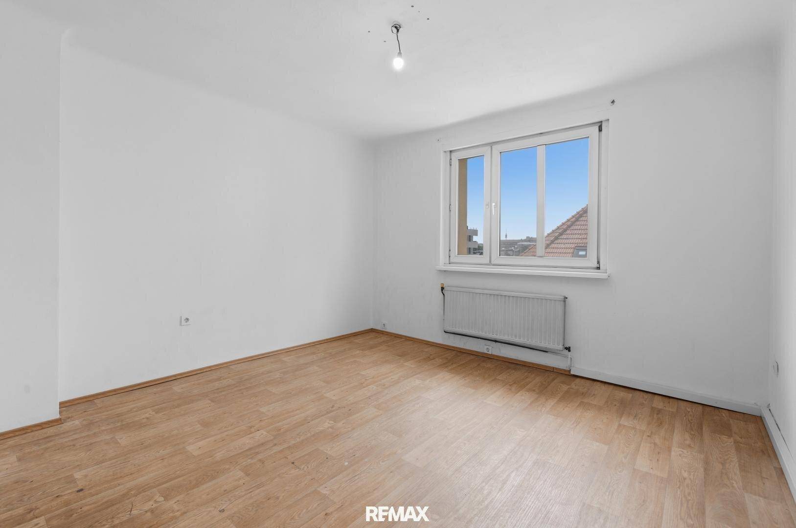 Leeres, helles Zimmer mit Holzboden und Fenster, bereit zur individuellen Gestaltung.