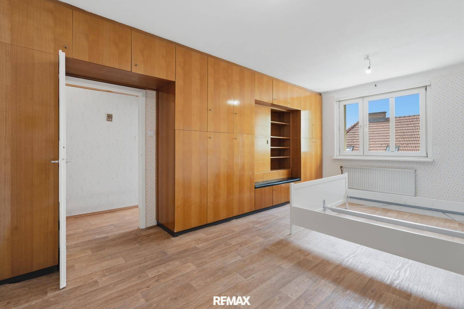 Geräumiges Schlafzimmer mit Holzboden, Einbauschränken und Fenster.