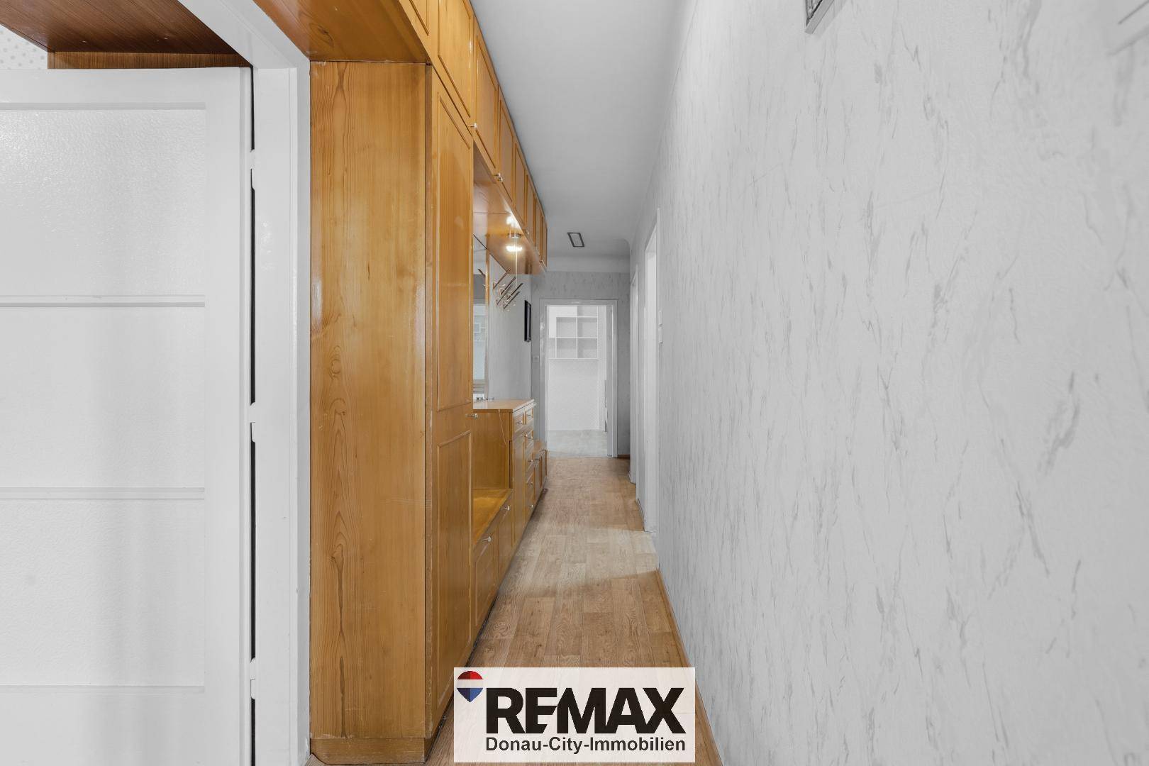 Langer Flur mit Laminatboden und Holzverkleidung an der Wand.