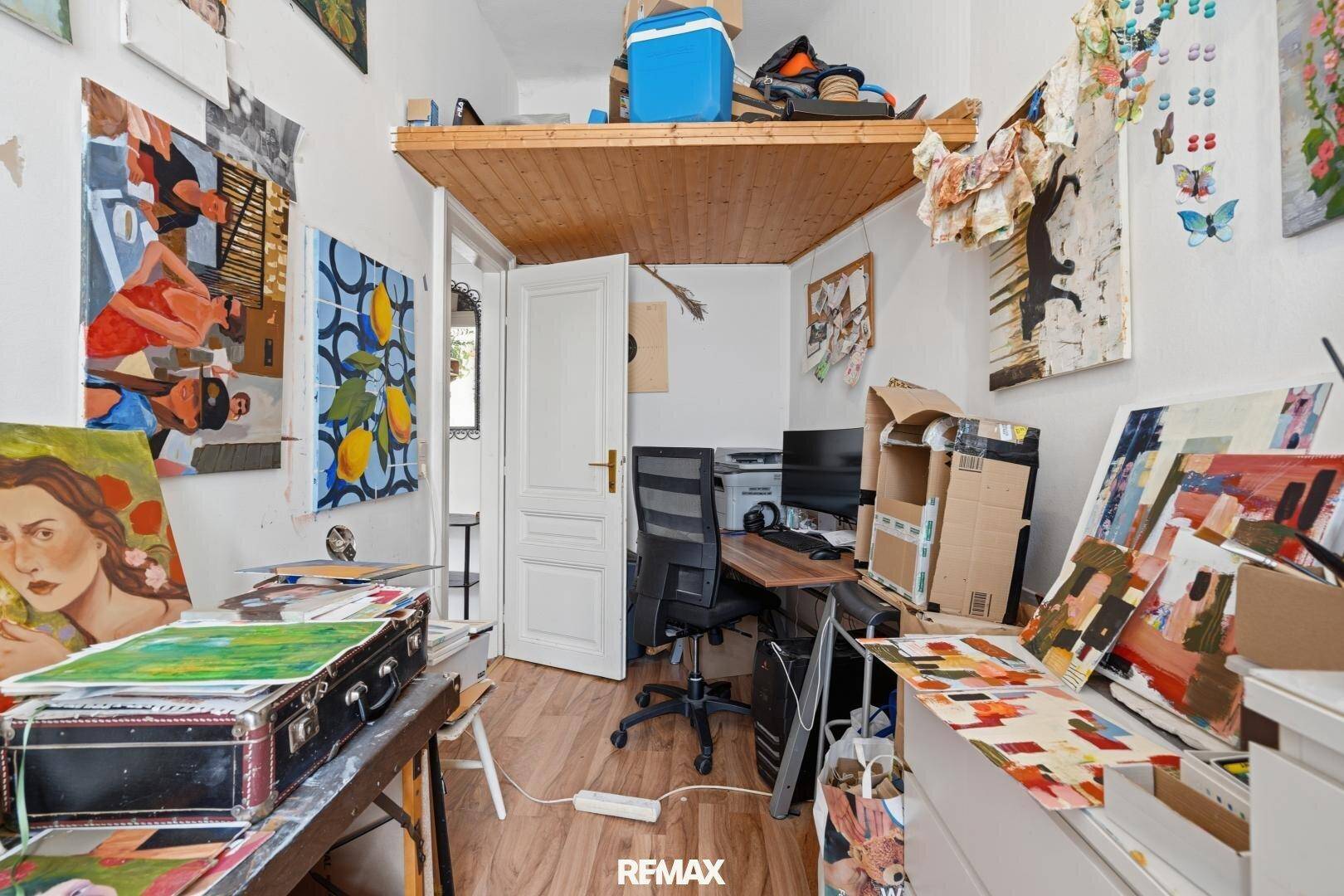 Arbeitszimmer mit Schreibtisch, Bürostuhl und einer erhöhten Holzplattform, die zusätzlichen Stauraum bietet.