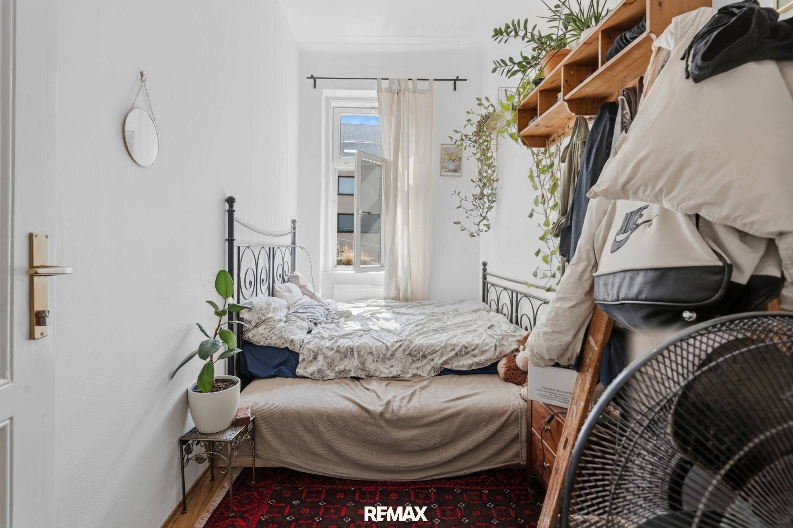 Schlafzimmer mit schmiedeeisernem Bett, Teppich und Fenster mit Vorhängen, das eine ruhige Rückzugsmöglichkeit bietet.