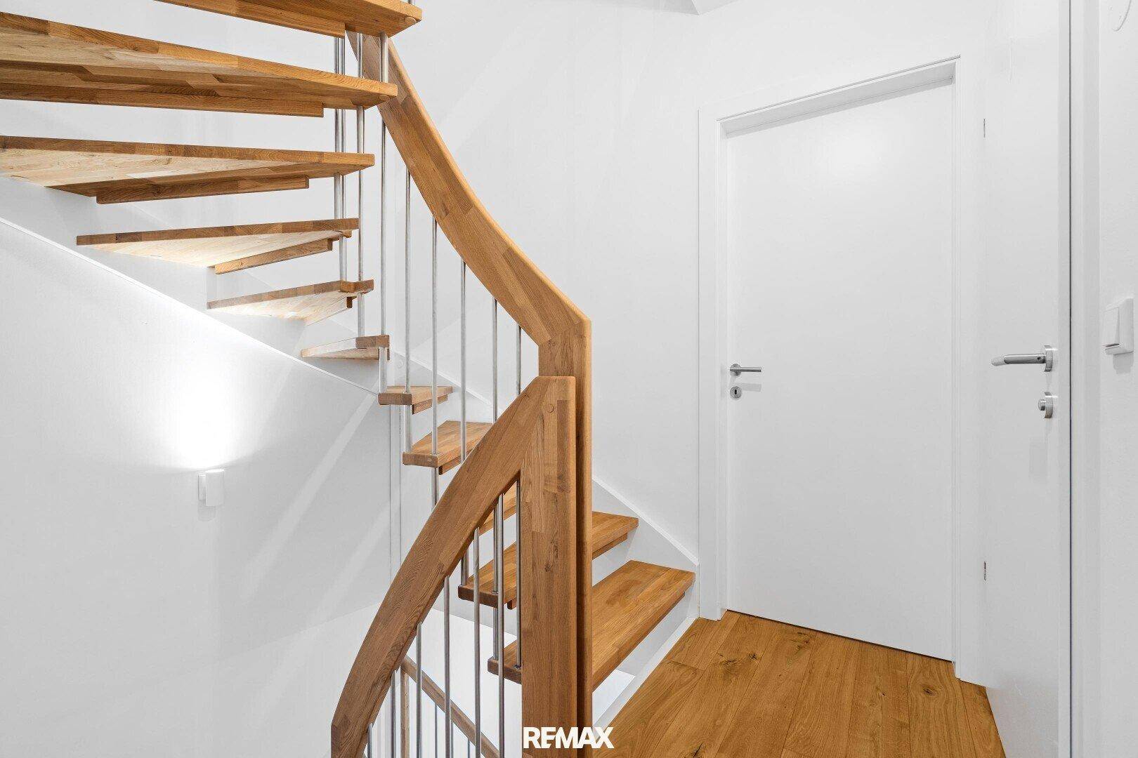 Detailansicht einer eleganten Holztreppe mit weißer Wand und Tür.