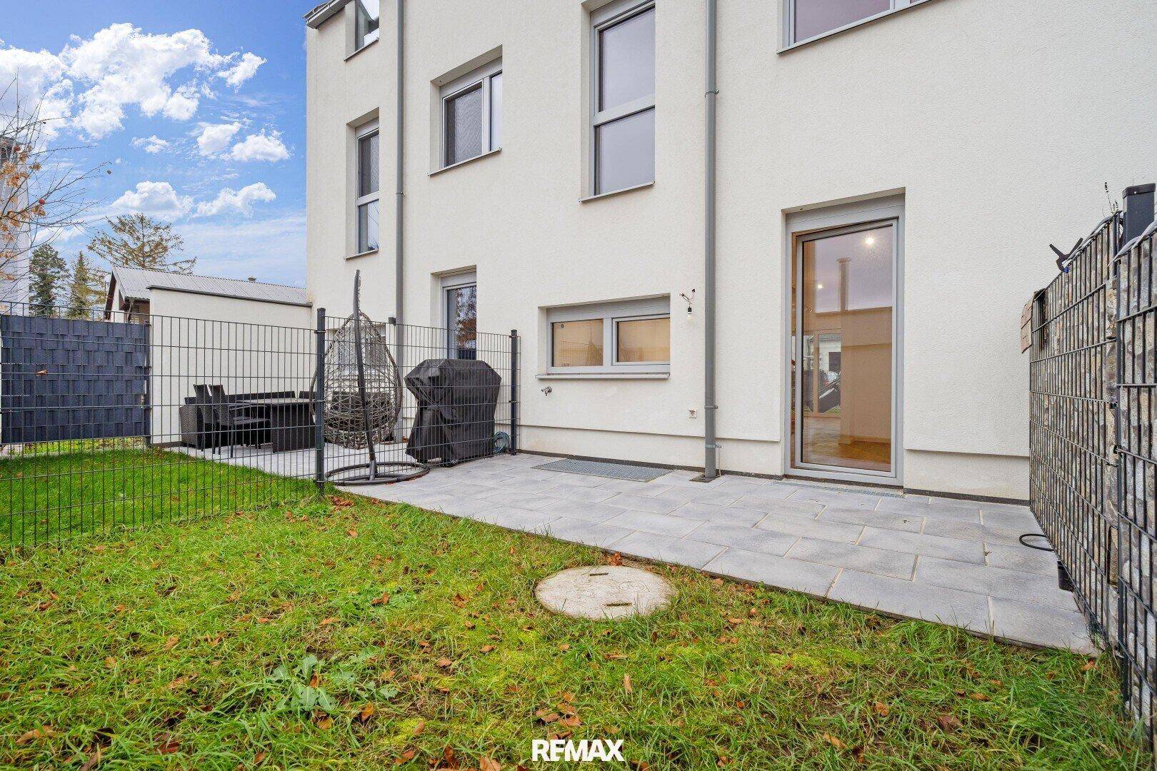 Hinterhof mit kleiner Rasenfläche, Terrasse und Outdoor-Sitzbereich für entspannte Stunden.