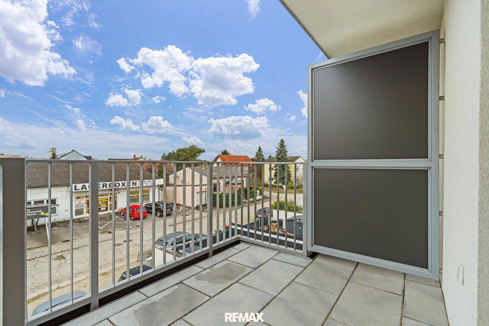 Sonniger Balkon mit Metallgeländer und weitem Blick über die Umgebung und den Himmel.