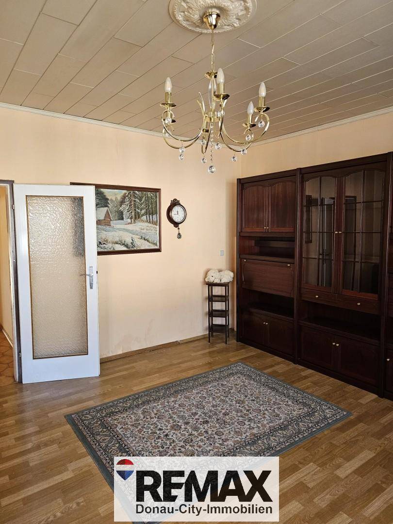 Helles Wohnzimmer mit Parkettboden, dunklen Holzschränken und einem Kronleuchter.