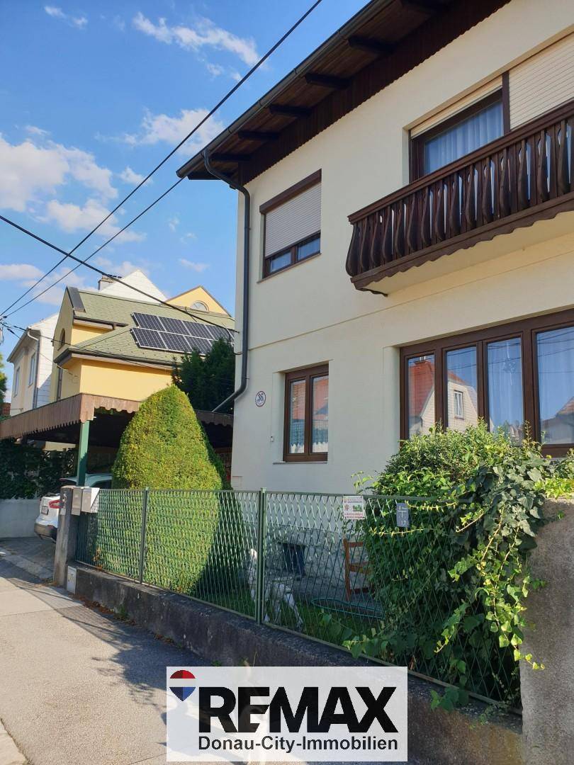 Vorderansicht des Hauses von der Straße mit Balkon und gepflegter Hecke.