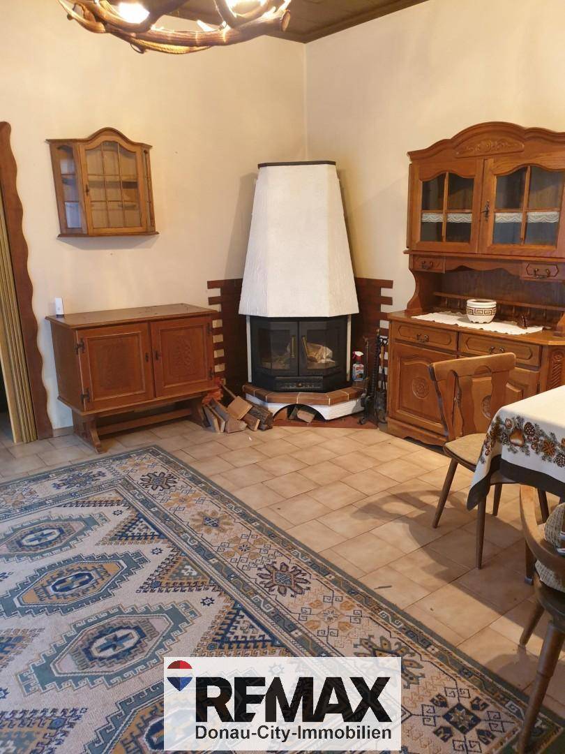 Gemütliches Wohnzimmer mit traditionellem Kamin, Fliesenboden und rustikalen Holzmöbeln.