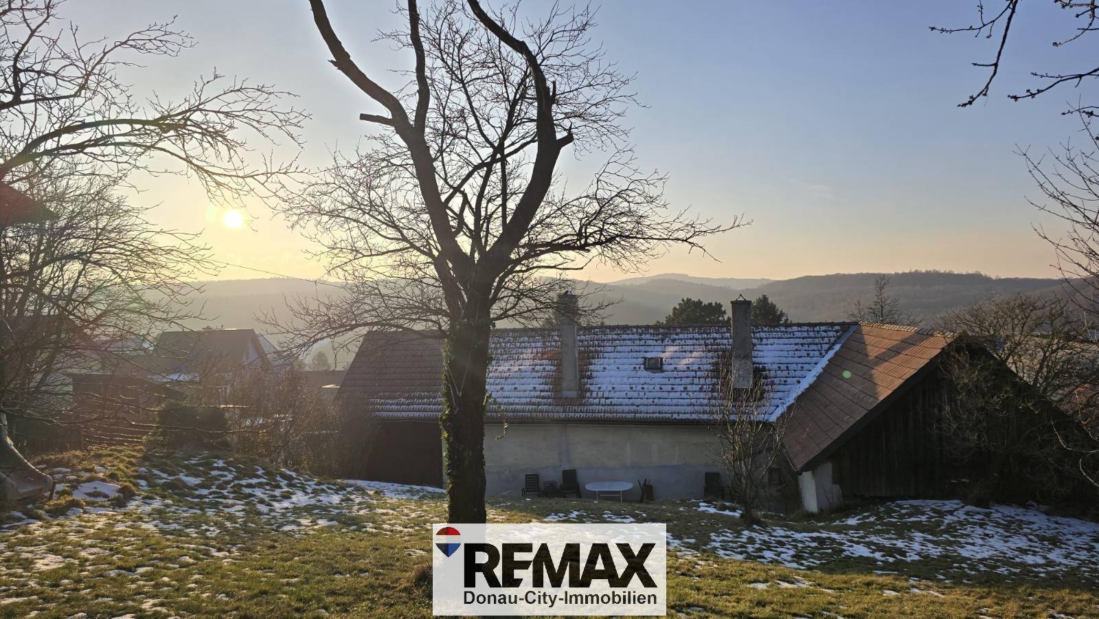 Haus und Garten in winterlicher Abendstimmung, beleuchtet von der tiefstehenden Sonne.