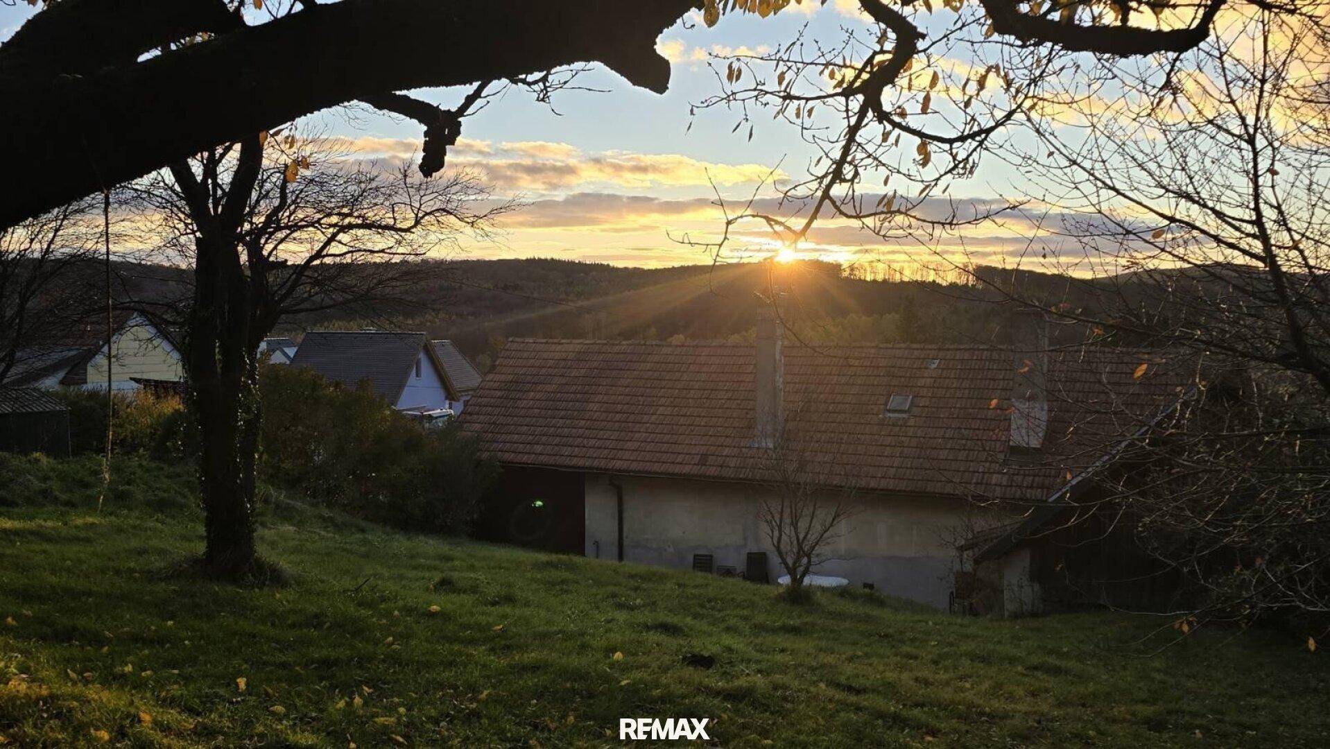 Malerischer Sonnenuntergang über einer ländlichen Landschaft mit Häusern und Bäumen im Herbst.