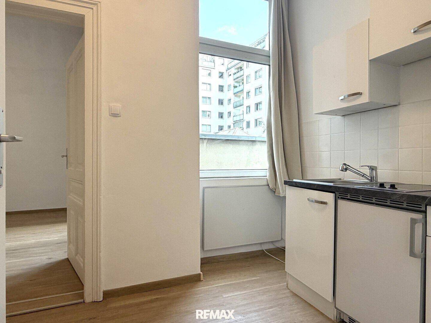 Küchenzeile mit Fensterblick auf umliegende Gebäude, hell und praktisch eingerichtet.