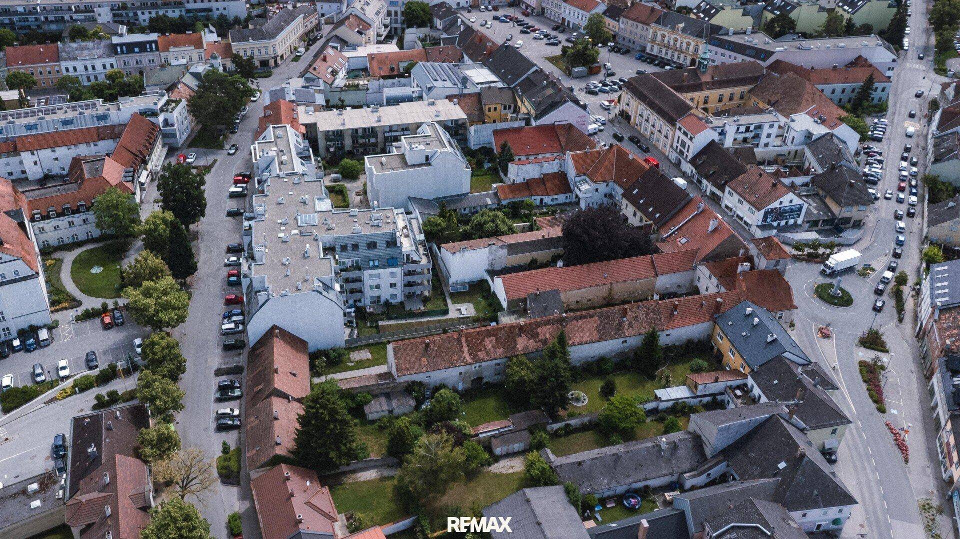 Luftaufnahme eines städtischen Gebiets mit Wohngebäuden und Straßen unter blauem Himmel.