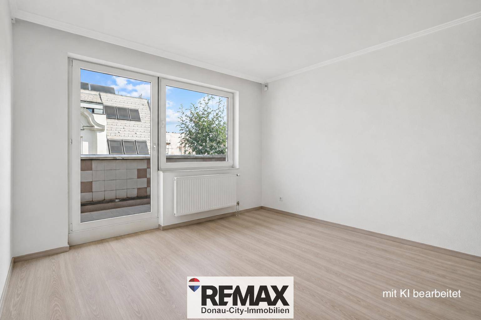 Heller Raum mit Laminatboden und großem Fenster mit Zugang zu einem kleinen Außenbereich.