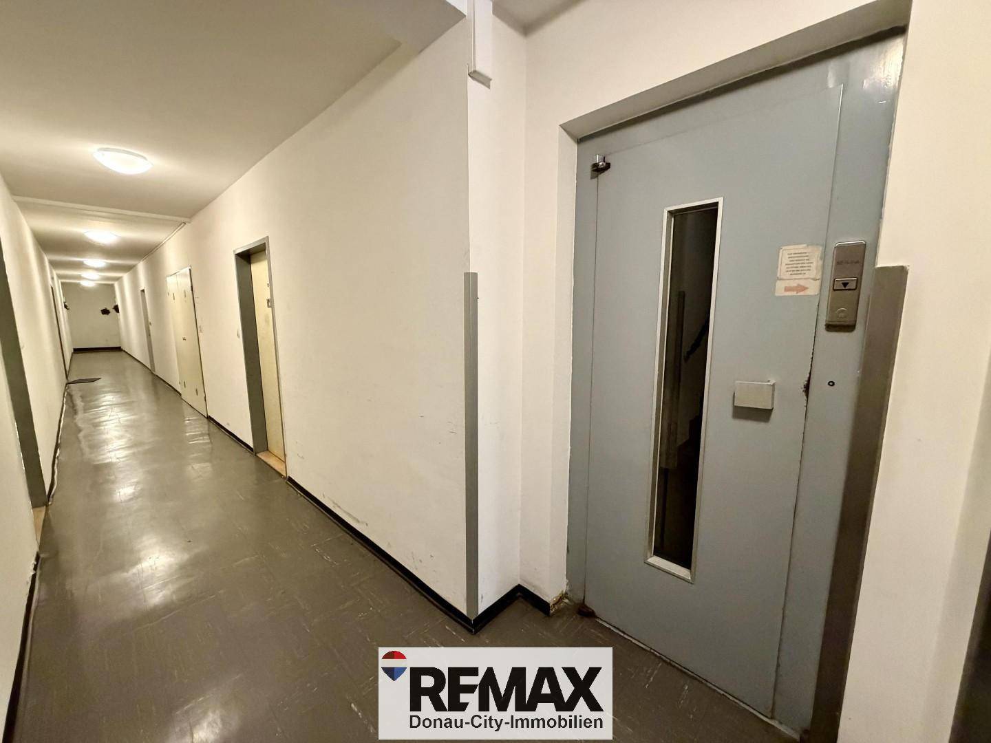 Langer Flur im Gebäude mit Zugang zum Aufzug und weiteren Wohnungen.