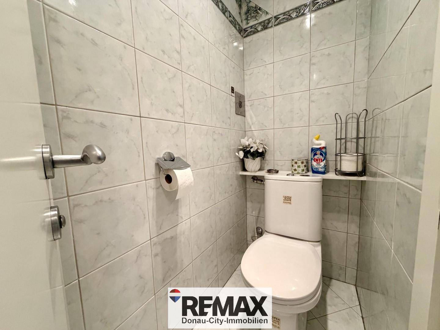 Separates WC mit Toilette und hell gefliesten Wänden.