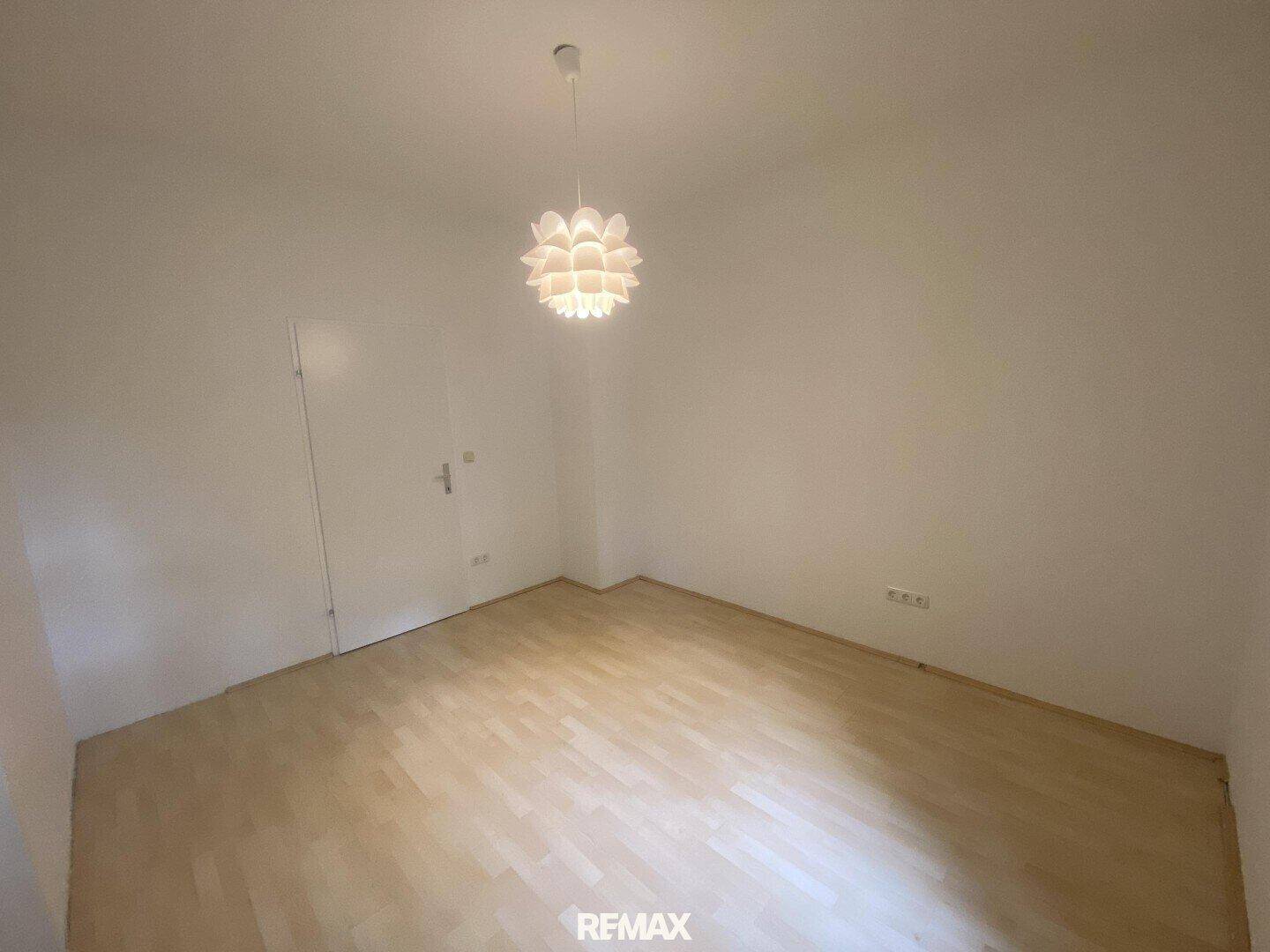 Leeres Zimmer mit Parkettboden und weiß gestrichenen Wänden, bereit zur individuellen Gestaltung.
